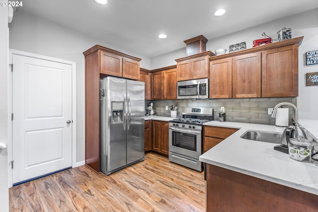 kitchen with backsplash, appliances with stainless steel finishes, sink, and light wood-type flooring