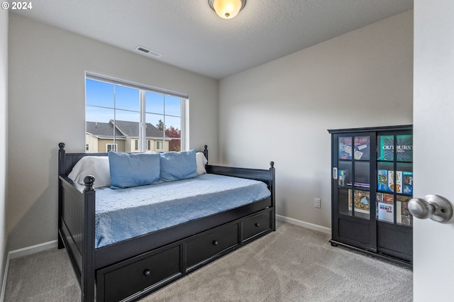 bedroom featuring a textured ceiling and light colored carpet