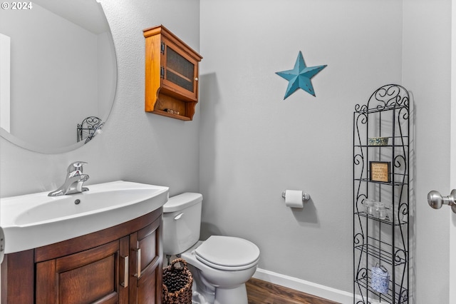 bathroom with toilet, hardwood / wood-style floors, and vanity