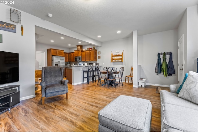 living room with a textured ceiling and light wood-type flooring