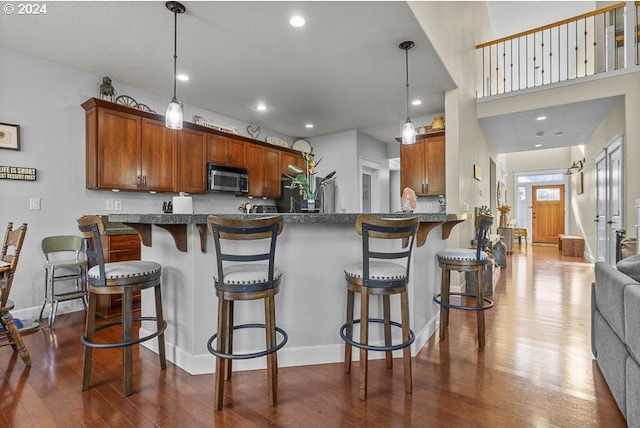 kitchen featuring decorative light fixtures, kitchen peninsula, dark wood-type flooring, and a breakfast bar area