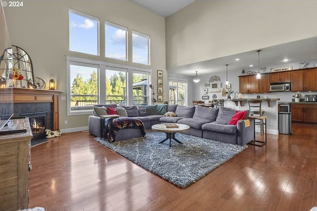 living room featuring a tile fireplace, a towering ceiling, and dark hardwood / wood-style floors