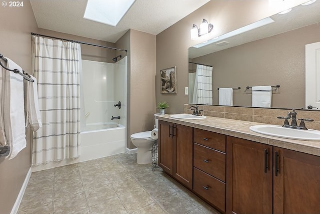 full bathroom featuring shower / bath combo, vanity, a skylight, toilet, and a textured ceiling