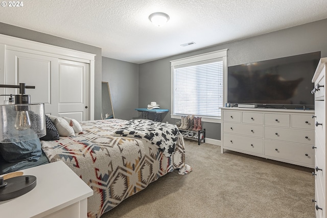 bedroom featuring a textured ceiling and light carpet