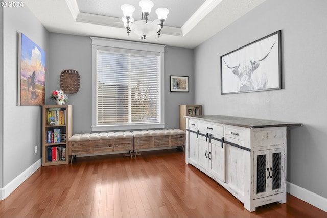 living area featuring a raised ceiling, a notable chandelier, and light wood-type flooring