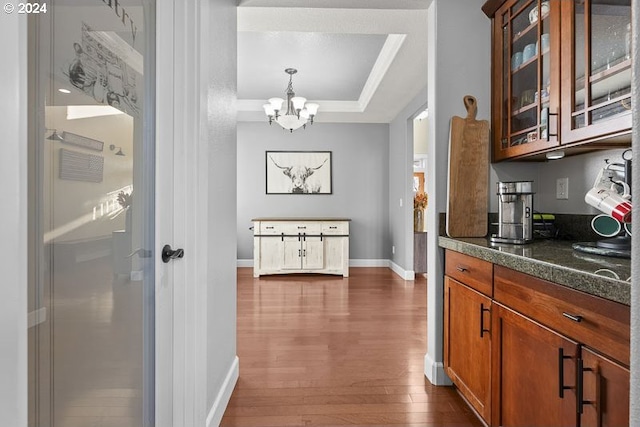 kitchen featuring pendant lighting, a raised ceiling, dark wood-type flooring, and an inviting chandelier