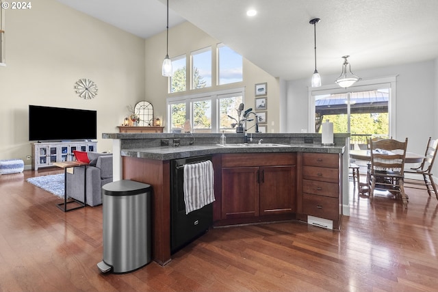 kitchen with pendant lighting, dishwasher, dark wood-type flooring, a high ceiling, and sink