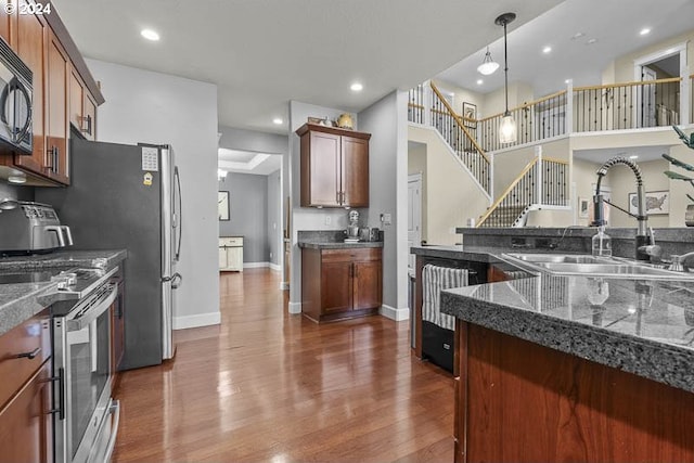 kitchen with stainless steel range oven, sink, hanging light fixtures, and dark hardwood / wood-style floors