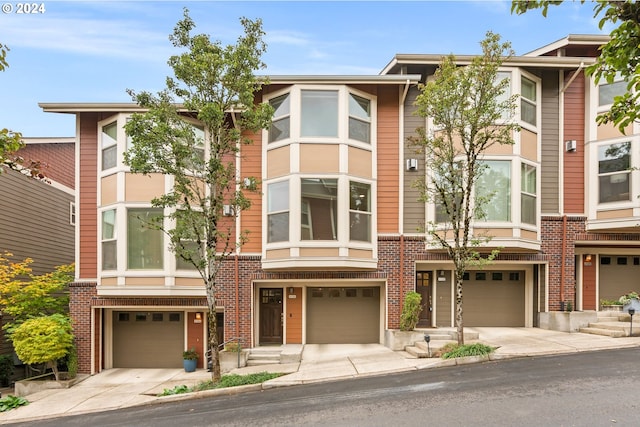 townhome / multi-family property featuring brick siding, driveway, and an attached garage