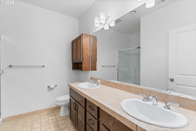 bathroom with a shower with door, toilet, vanity, and tile patterned flooring