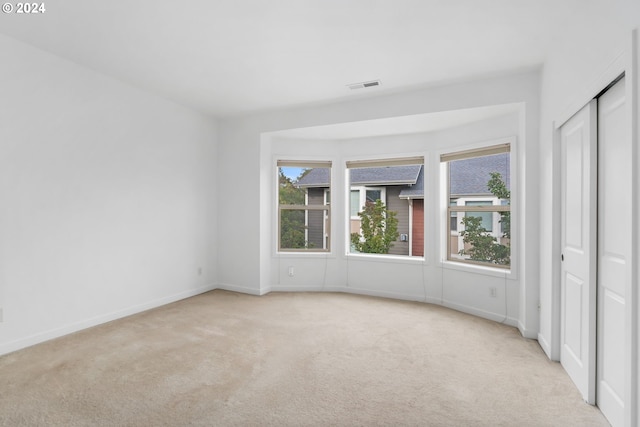 unfurnished bedroom featuring light carpet and a closet