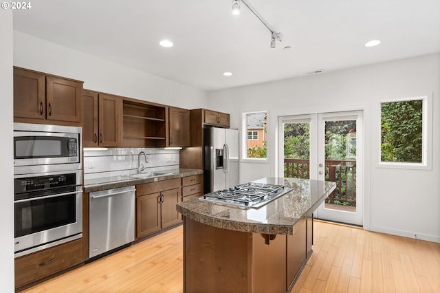 kitchen with stainless steel appliances, a sink, a kitchen breakfast bar, tile counters, and open shelves