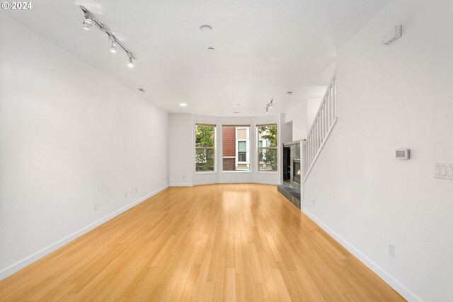 unfurnished living room featuring rail lighting and light wood-type flooring