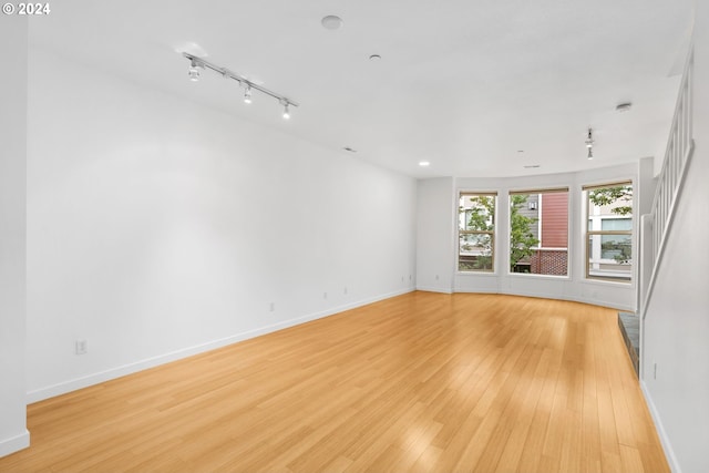 unfurnished room with track lighting and light hardwood / wood-style floors