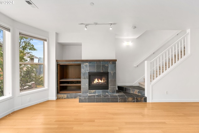 unfurnished living room with a fireplace, hardwood / wood-style flooring, and a healthy amount of sunlight