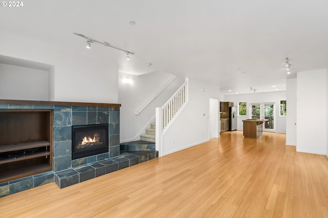 unfurnished living room with hardwood / wood-style flooring, a tile fireplace, and rail lighting