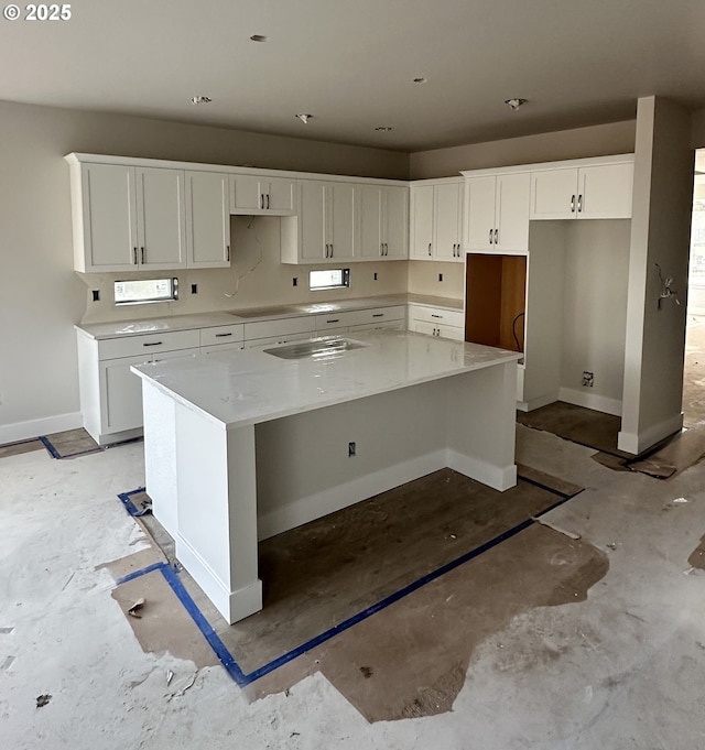 kitchen featuring white cabinetry, a center island, stovetop, and light stone counters