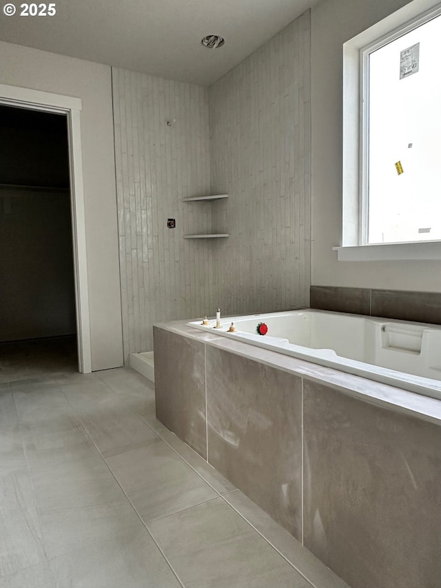 bathroom with tile patterned flooring and tiled tub