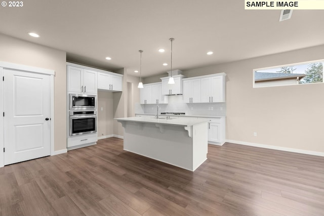 kitchen with wood-type flooring, appliances with stainless steel finishes, white cabinets, and a skylight