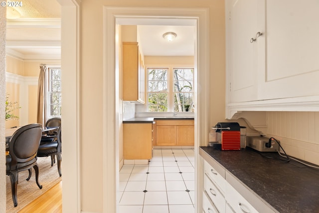 kitchen with light brown cabinets, light wood-type flooring, and crown molding