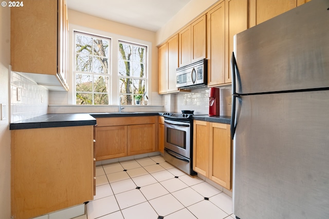 kitchen featuring tasteful backsplash, sink, light tile patterned floors, and appliances with stainless steel finishes