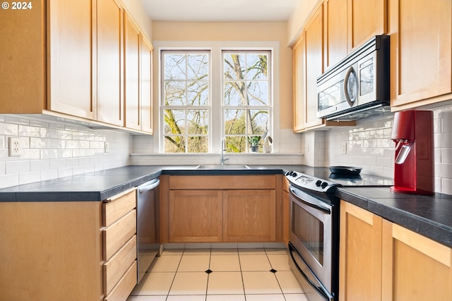 kitchen with decorative backsplash, sink, light tile patterned floors, and stainless steel appliances