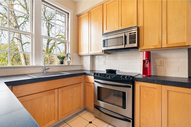 kitchen featuring backsplash, light tile patterned flooring, sink, and stainless steel appliances