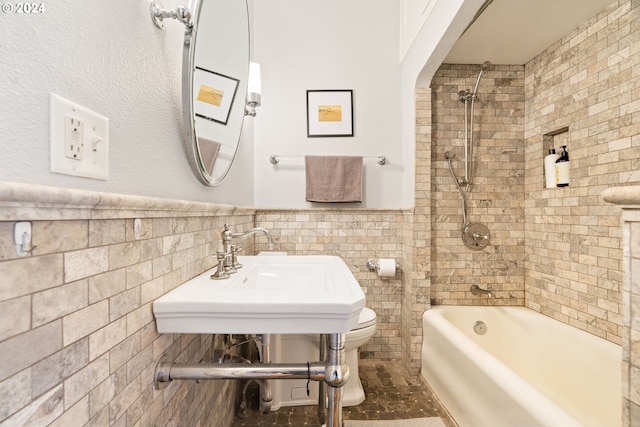 full bathroom with sink, toilet, tiled shower / bath, and tile walls