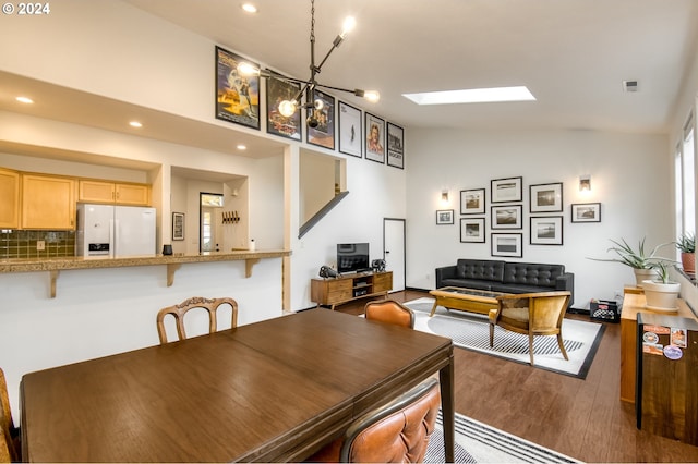 dining area with vaulted ceiling with skylight, dark hardwood / wood-style floors, and a notable chandelier