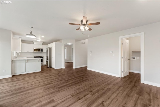 unfurnished living room featuring dark hardwood / wood-style flooring, ceiling fan, and sink