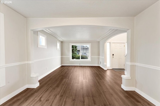 unfurnished room with crown molding and dark wood-type flooring