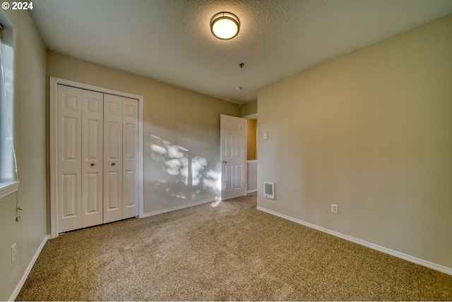 unfurnished bedroom with carpet flooring, a textured ceiling, and a closet