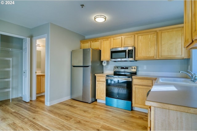 kitchen with light brown cabinetry, sink, appliances with stainless steel finishes, and light hardwood / wood-style flooring