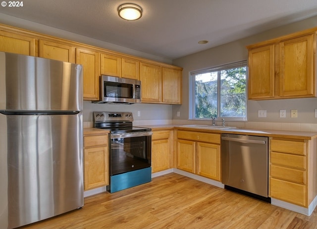 kitchen featuring light wood-type flooring, sink, and appliances with stainless steel finishes