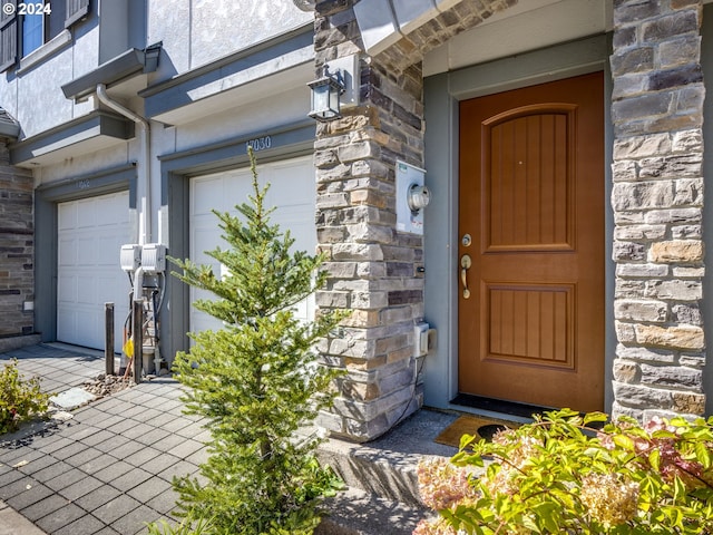 doorway to property with stone siding and an attached garage