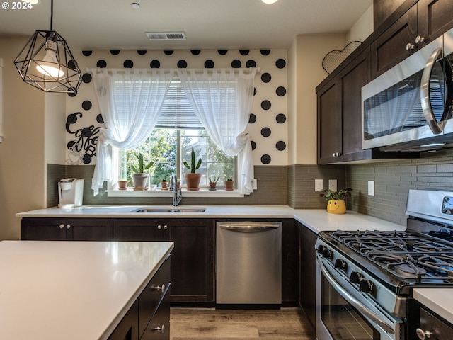 kitchen with stainless steel appliances, sink, backsplash, and light hardwood / wood-style floors