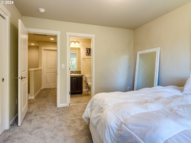 bedroom with light colored carpet and connected bathroom