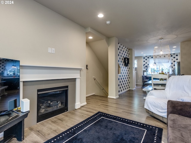 living room with hardwood / wood-style flooring, a notable chandelier, and a tile fireplace