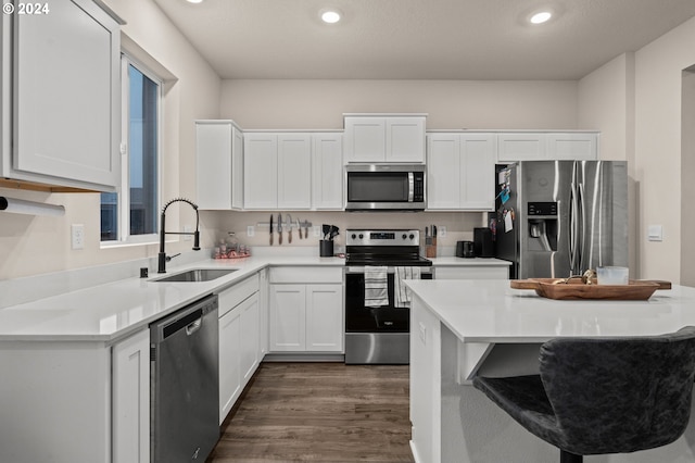 kitchen featuring dark wood-type flooring, white cabinets, sink, a breakfast bar area, and stainless steel appliances