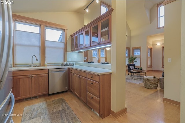 285 23rd St, Astoria, OR 97103 - kitchen featuring appliances with stainless steel finishes, a sink, light wood finished floors, brown cabinetry, and glass insert cabinets