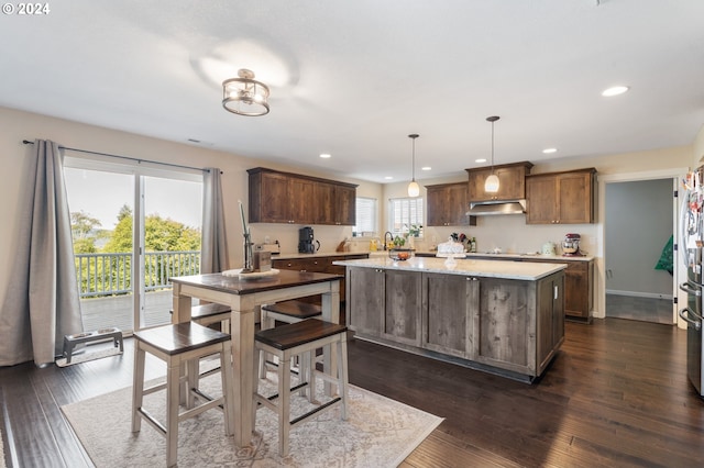 kitchen with pendant lighting, dark hardwood / wood-style floors, sink, and a kitchen island