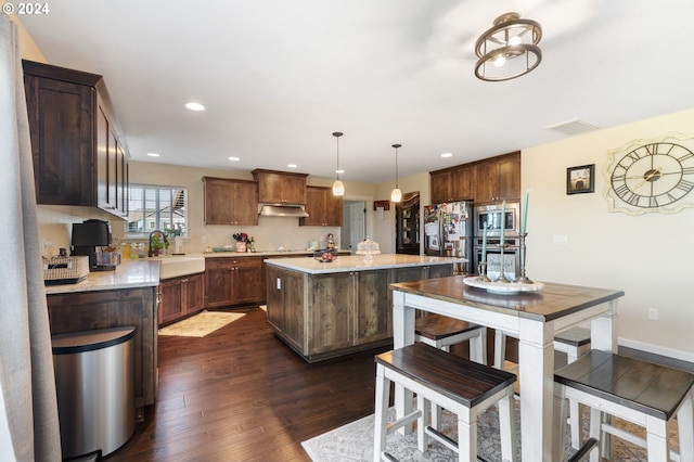 kitchen featuring a kitchen island, pendant lighting, sink, stainless steel appliances, and dark wood-type flooring