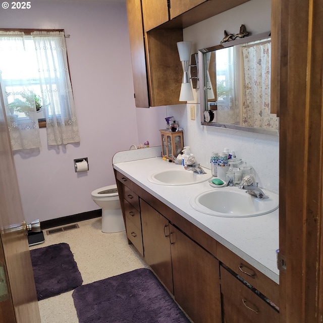 full bathroom featuring a sink, visible vents, toilet, and double vanity