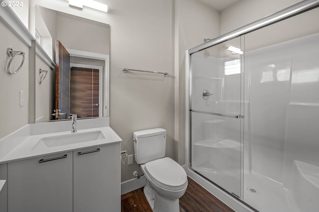 bathroom featuring vanity, toilet, wood-type flooring, and a shower with shower door