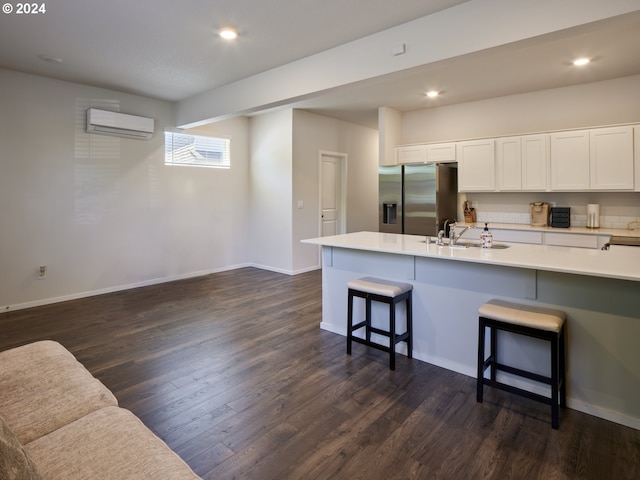 kitchen featuring a wall mounted air conditioner, stainless steel fridge with ice dispenser, dark hardwood / wood-style floors, white cabinetry, and a breakfast bar area