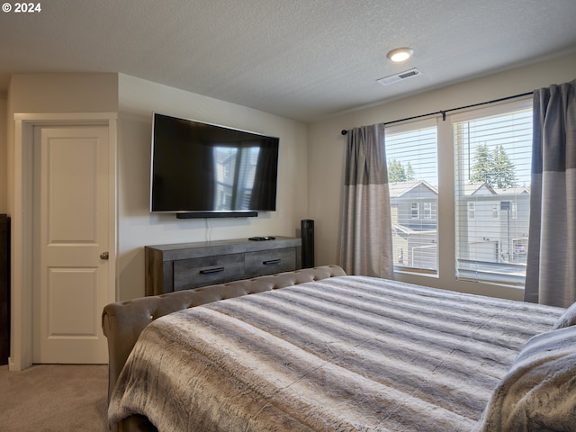 bedroom with light colored carpet and a textured ceiling