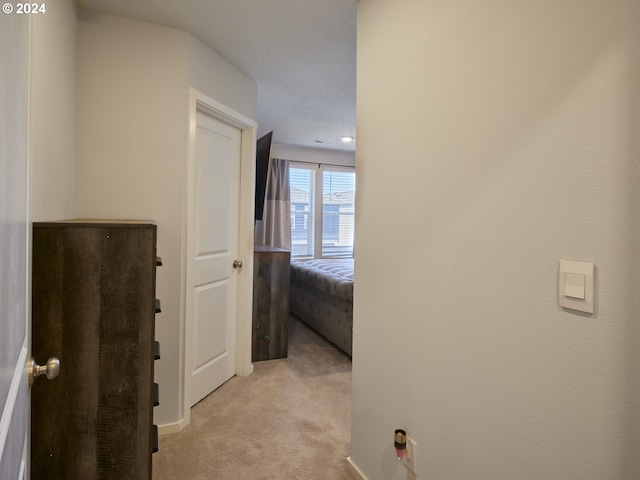 corridor featuring light carpet and a textured ceiling