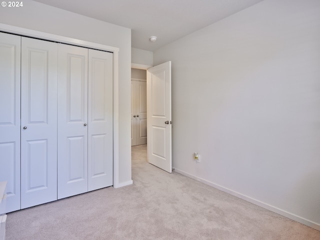 unfurnished bedroom with light carpet and a closet