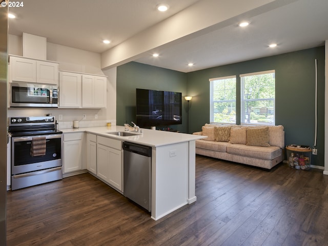 kitchen featuring kitchen peninsula, appliances with stainless steel finishes, white cabinetry, and dark wood-type flooring