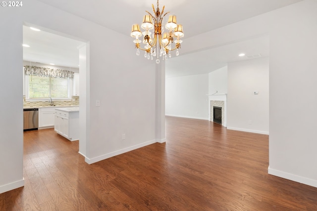 unfurnished dining area featuring a notable chandelier, a tiled fireplace, hardwood / wood-style floors, and sink